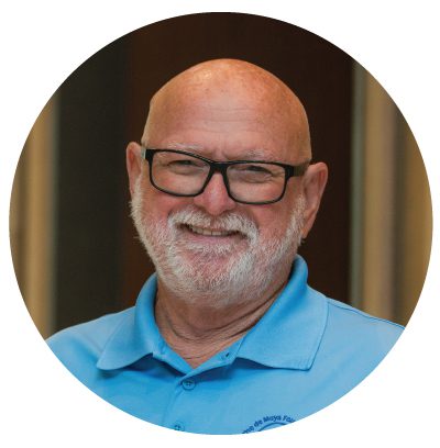 Smiling man in blue shirt and glasses.