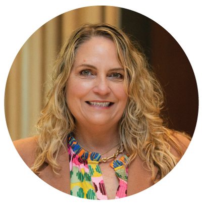Smiling woman with curly hair and necklace.