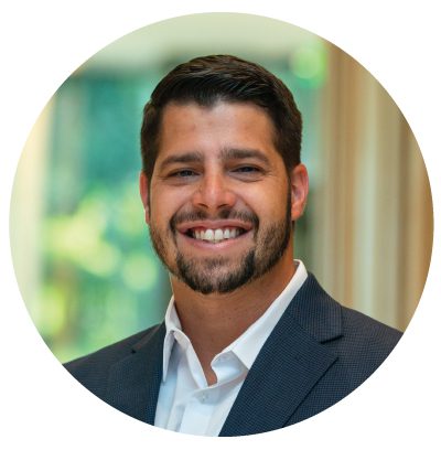 Smiling man in a suit, blurred background.